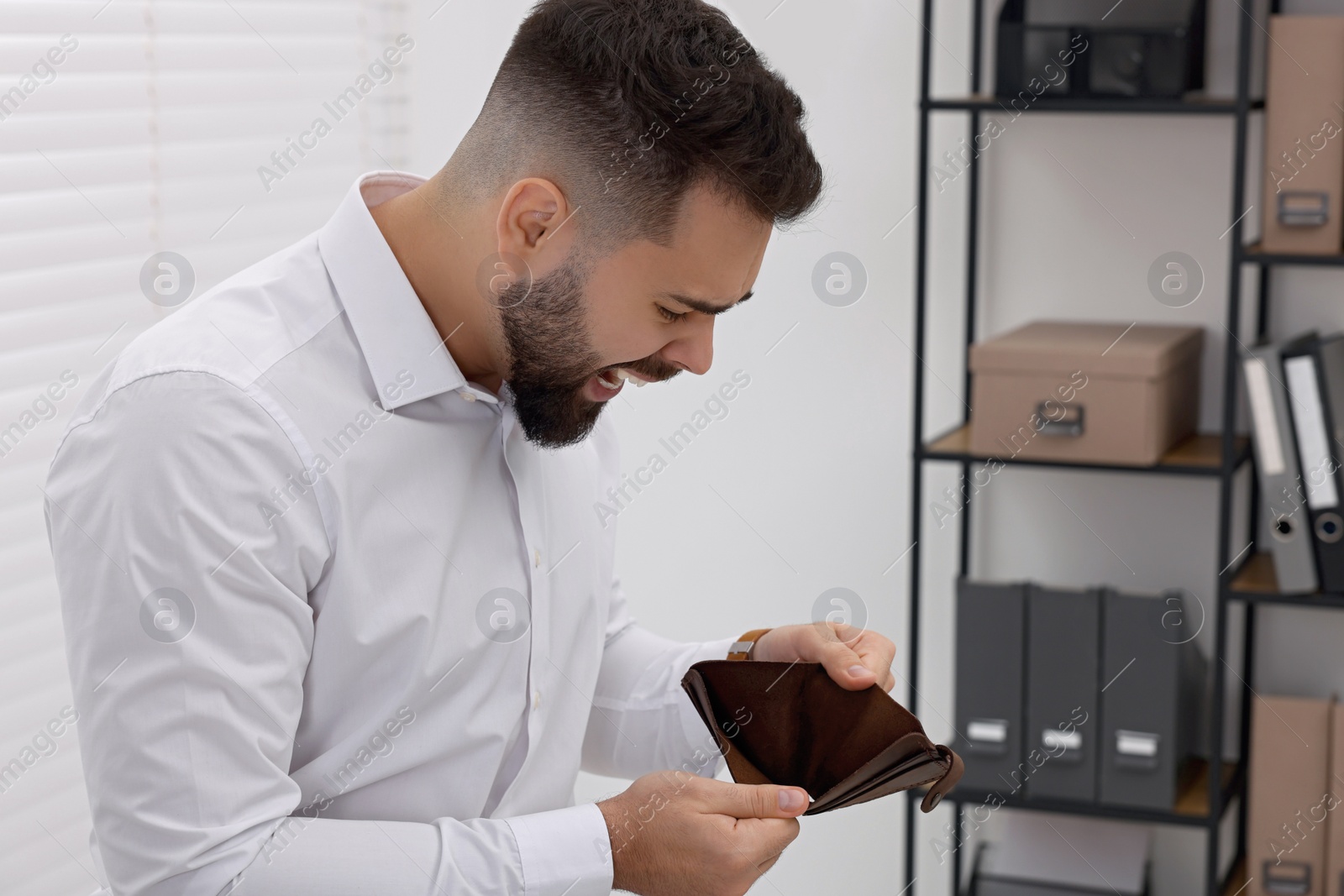 Photo of Angry man with empty wallet in office