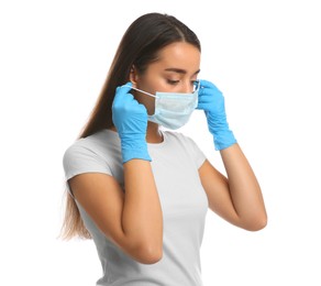 Photo of Woman in medical gloves putting on protective face mask against white background