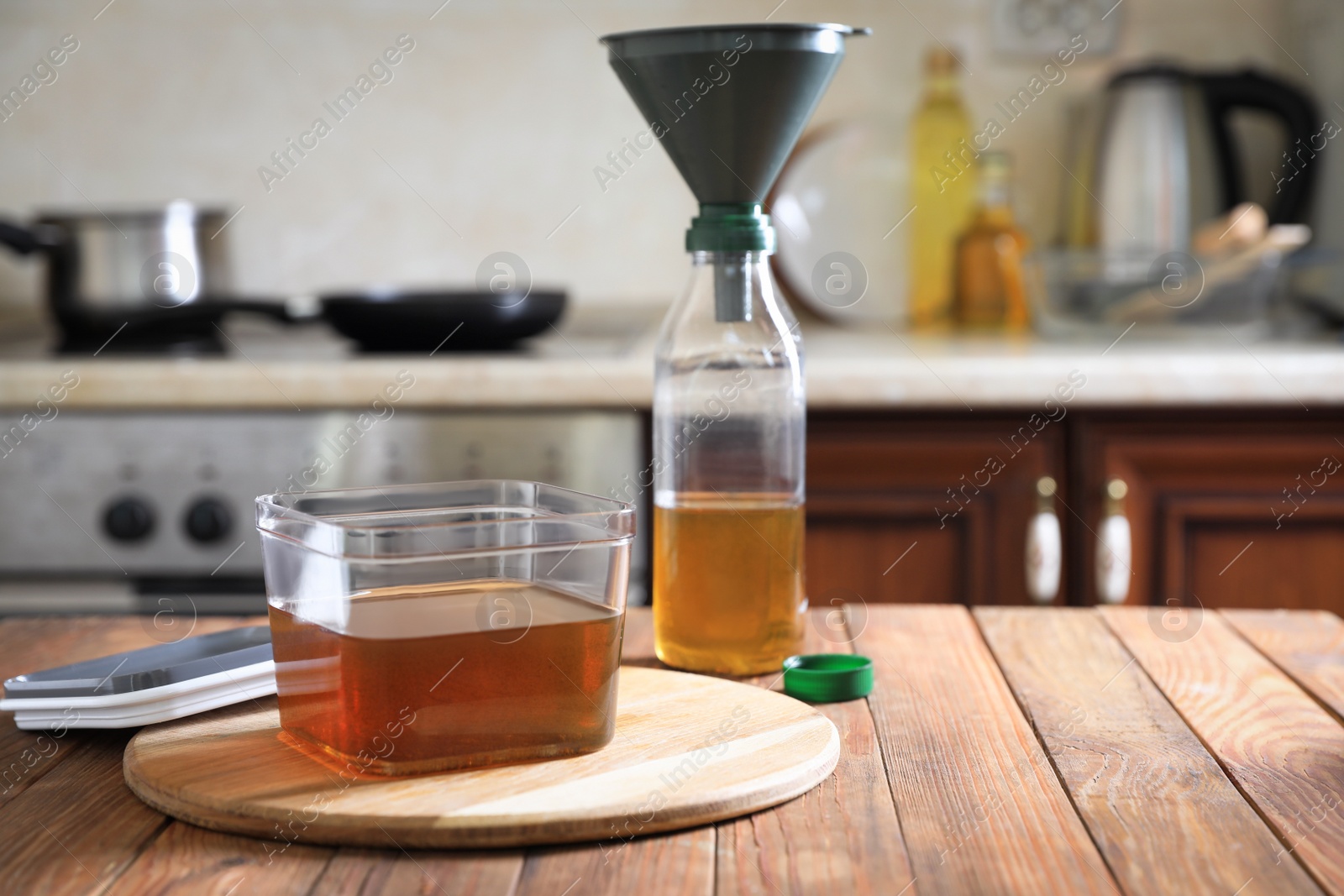 Photo of Used cooking oil on wooden table in kitchen, space for text