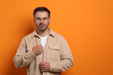 Photo of Portrait of man in stylish glasses on orange background, space for text