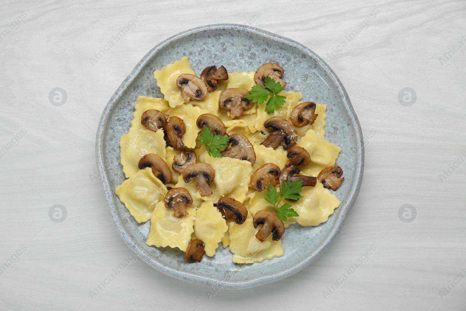 Photo of Delicious ravioli with mushrooms on white wooden table, top view