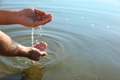 Man taking pure water from river, closeup. Nature healing power