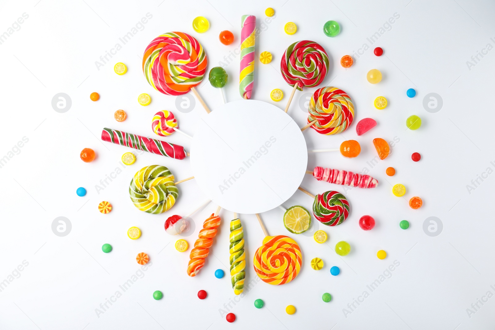 Photo of Different tasty candies and card with space for text on white background, top view