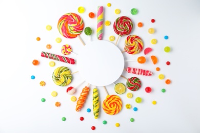 Different tasty candies and card with space for text on white background, top view