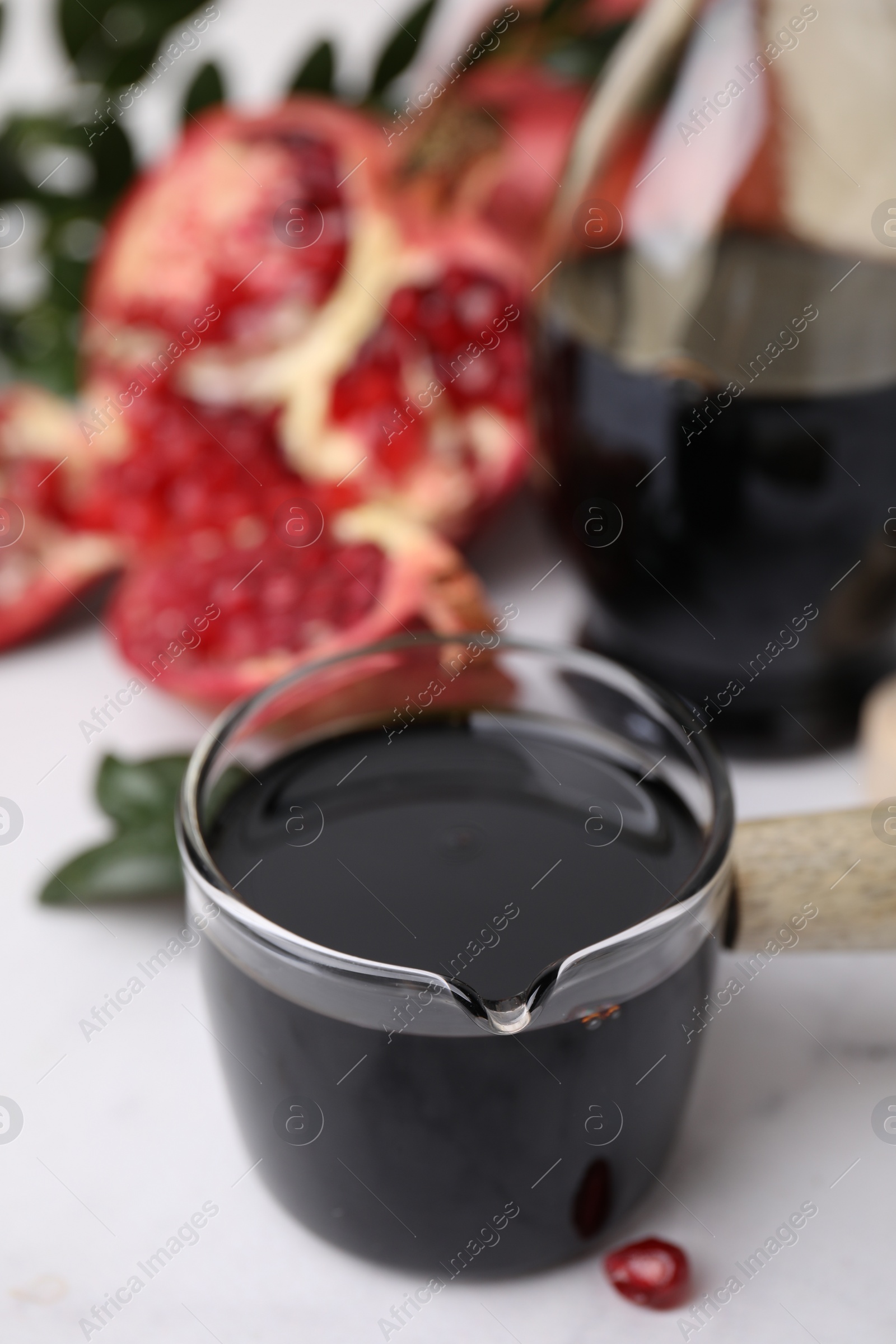 Photo of Tasty pomegranate sauce on white table, closeup