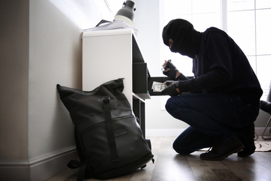 Thief taking money out of steel safe indoors