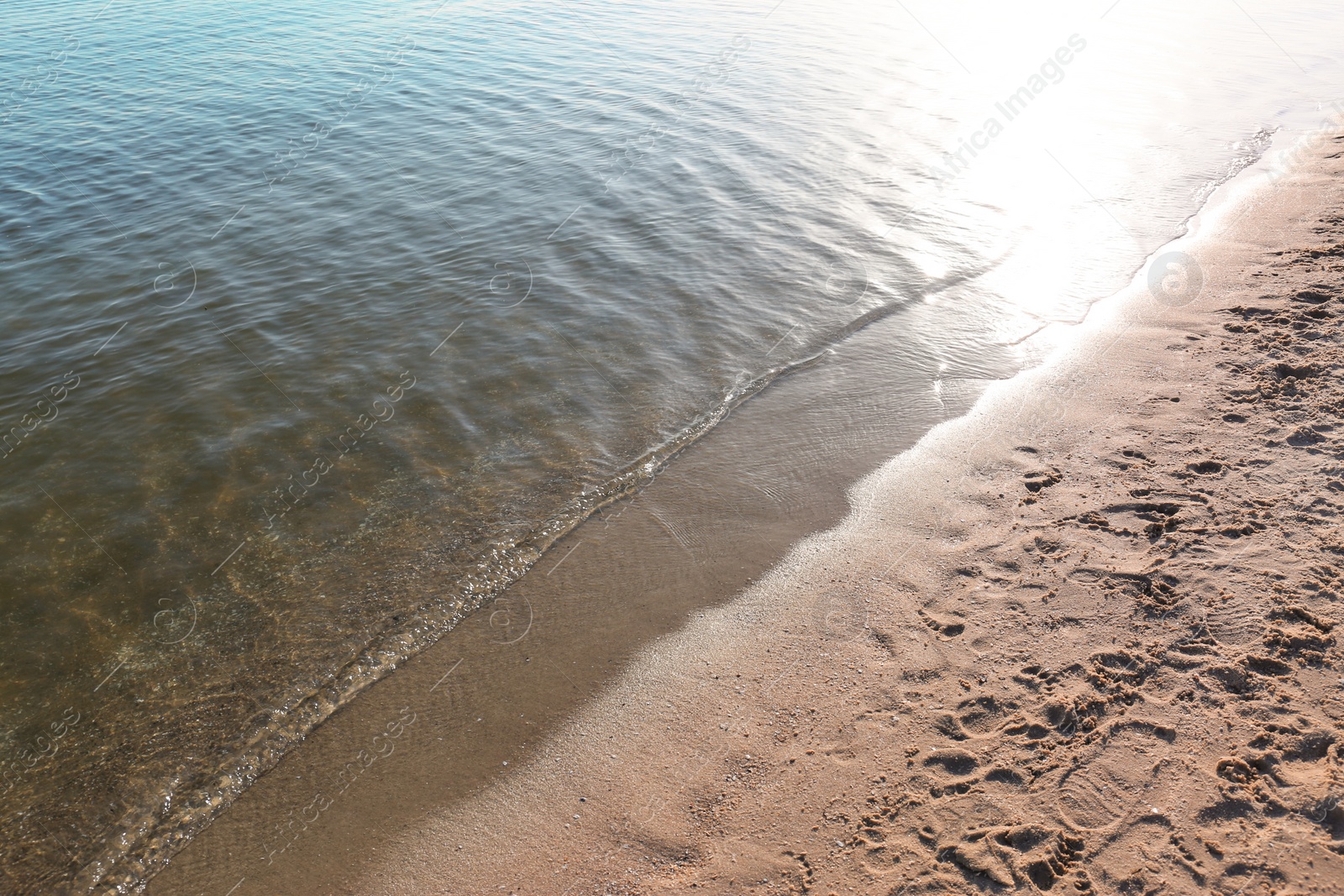 Photo of View of sea water and beach sand on sunny summer day
