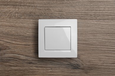 Photo of White plastic light switch on wooden background