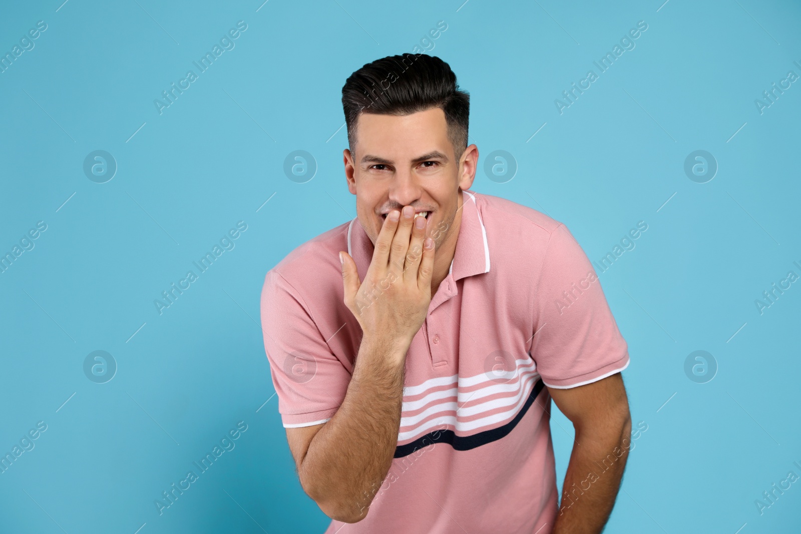 Photo of Handsome man laughing on light blue background. Funny joke