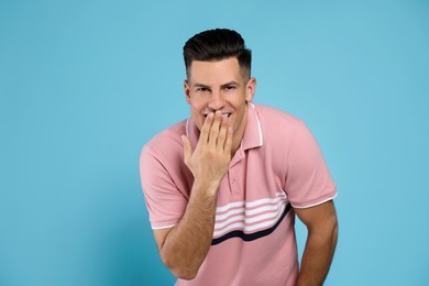 Handsome man laughing on light blue background. Funny joke