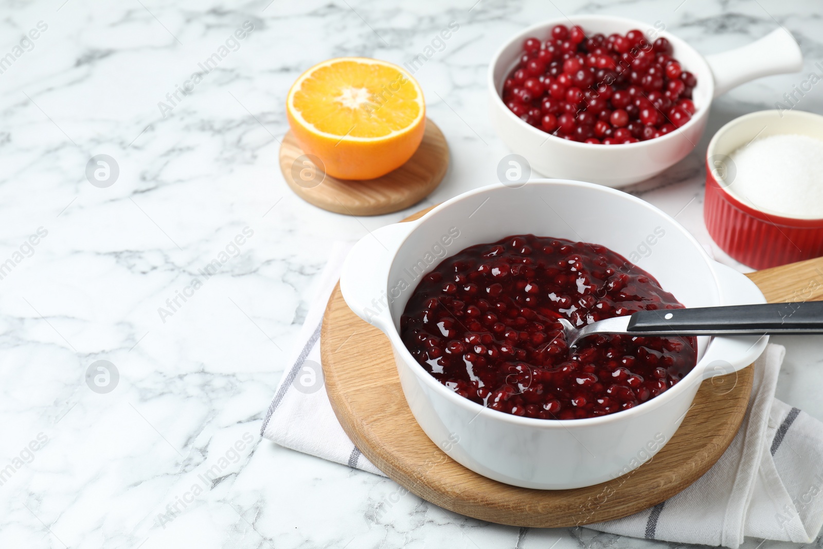 Photo of Fresh cranberry sauce in bowl served on white marble table, space for text