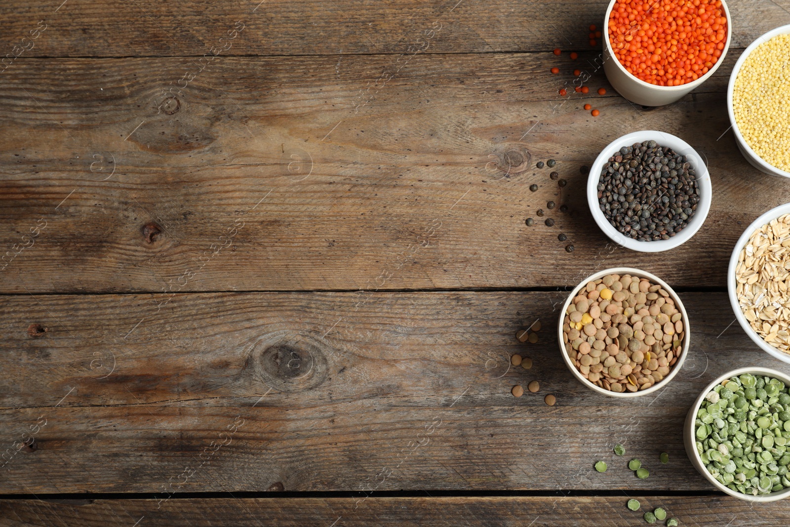 Photo of Flat lay composition with different types of legumes and cereals on wooden table, space for text. Organic grains