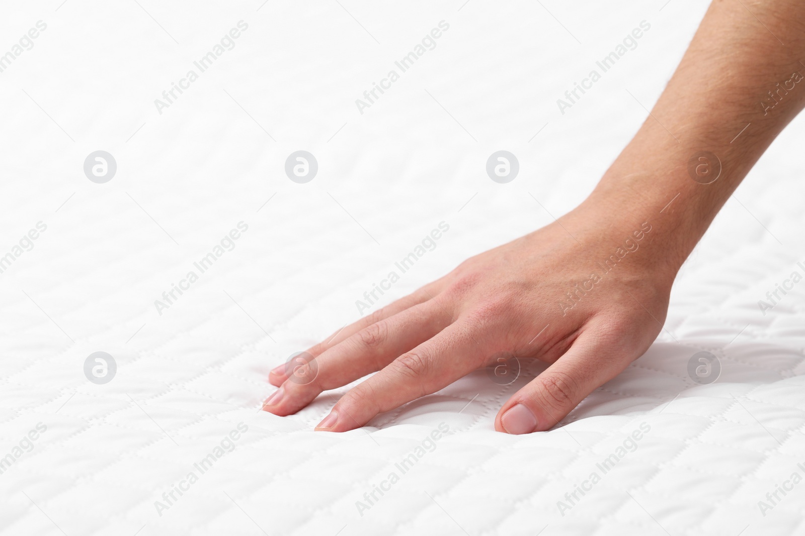 Photo of Man touching soft mattress, closeup. Space for text