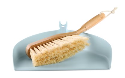 Photo of Light blue dustpan and wooden brush on white background