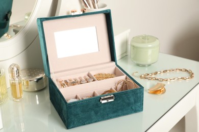 Photo of Elegant jewelry box with beautiful bijouterie, cosmetics and perfume on dressing table