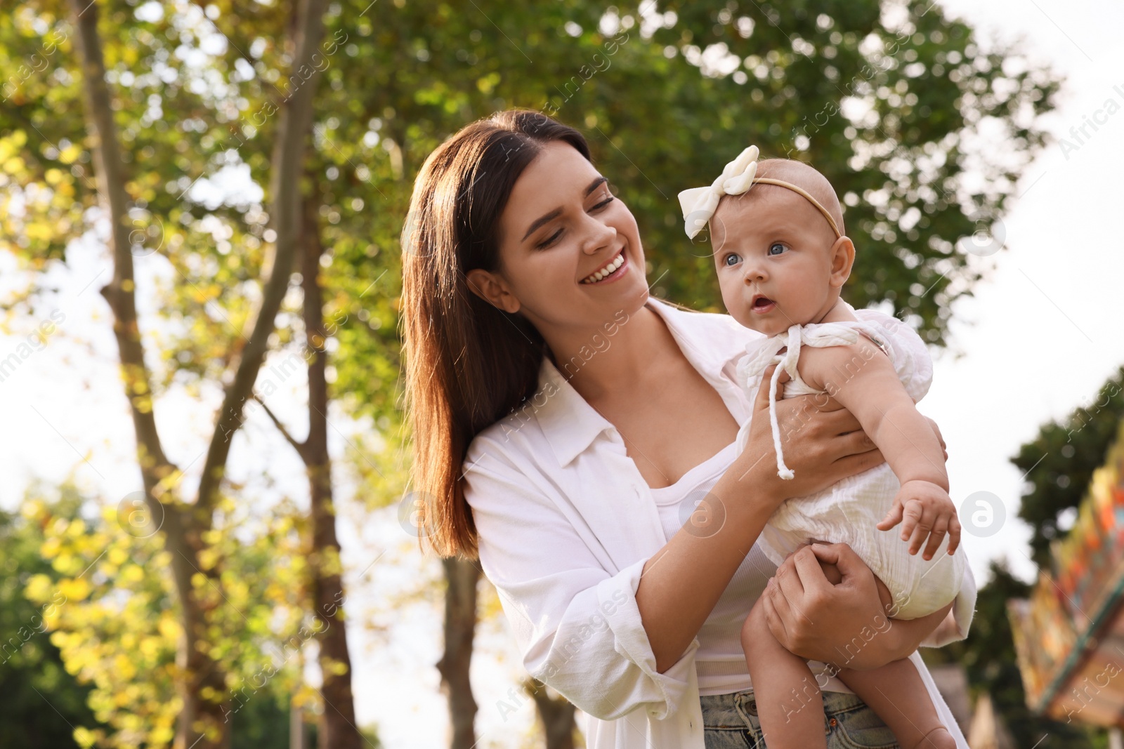 Photo of Happy mother with adorable baby walking on sunny day