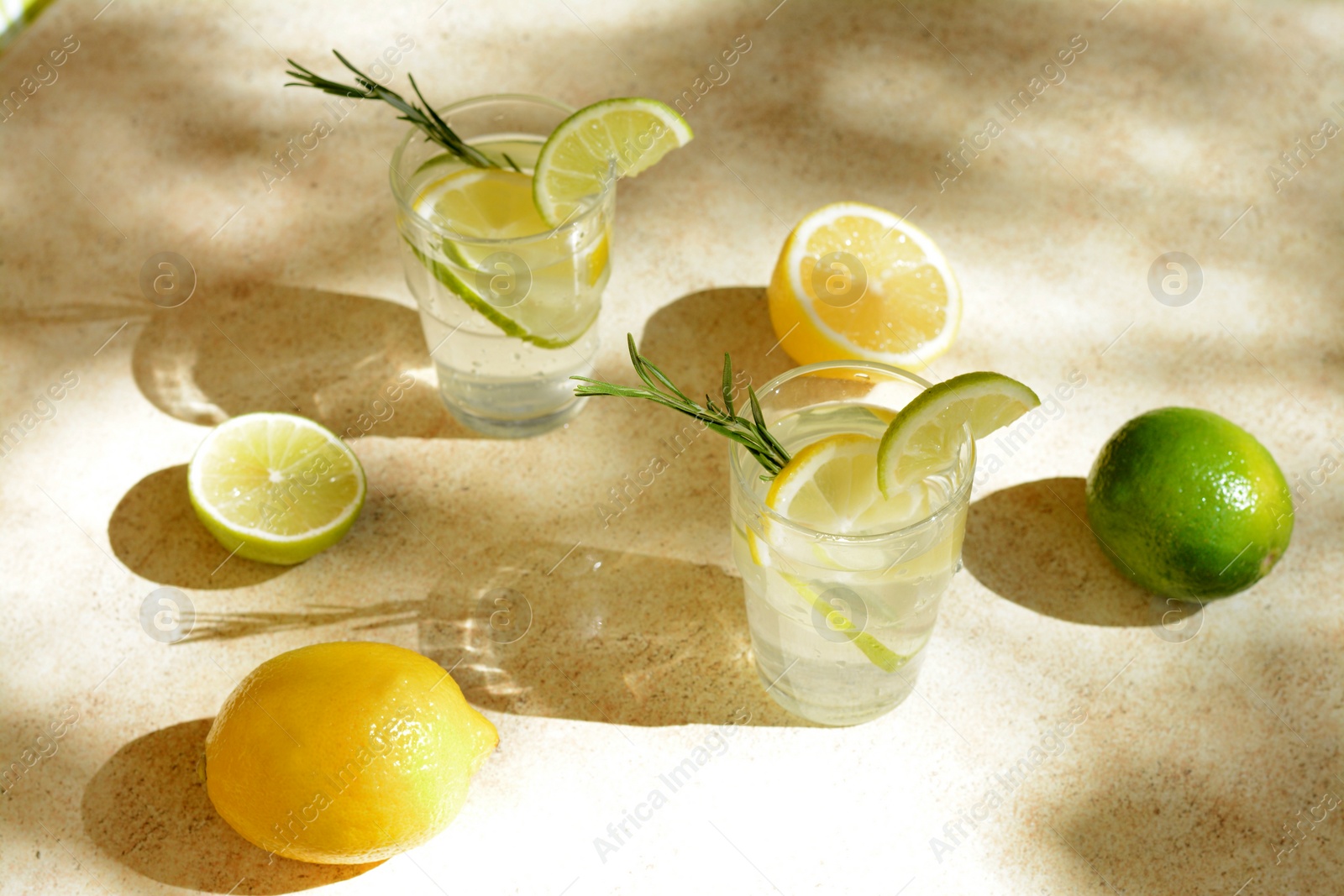 Photo of Glasses of summer refreshing lemonade and ingredients on light table