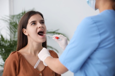 Doctor taking sample for DNA test from woman in clinic