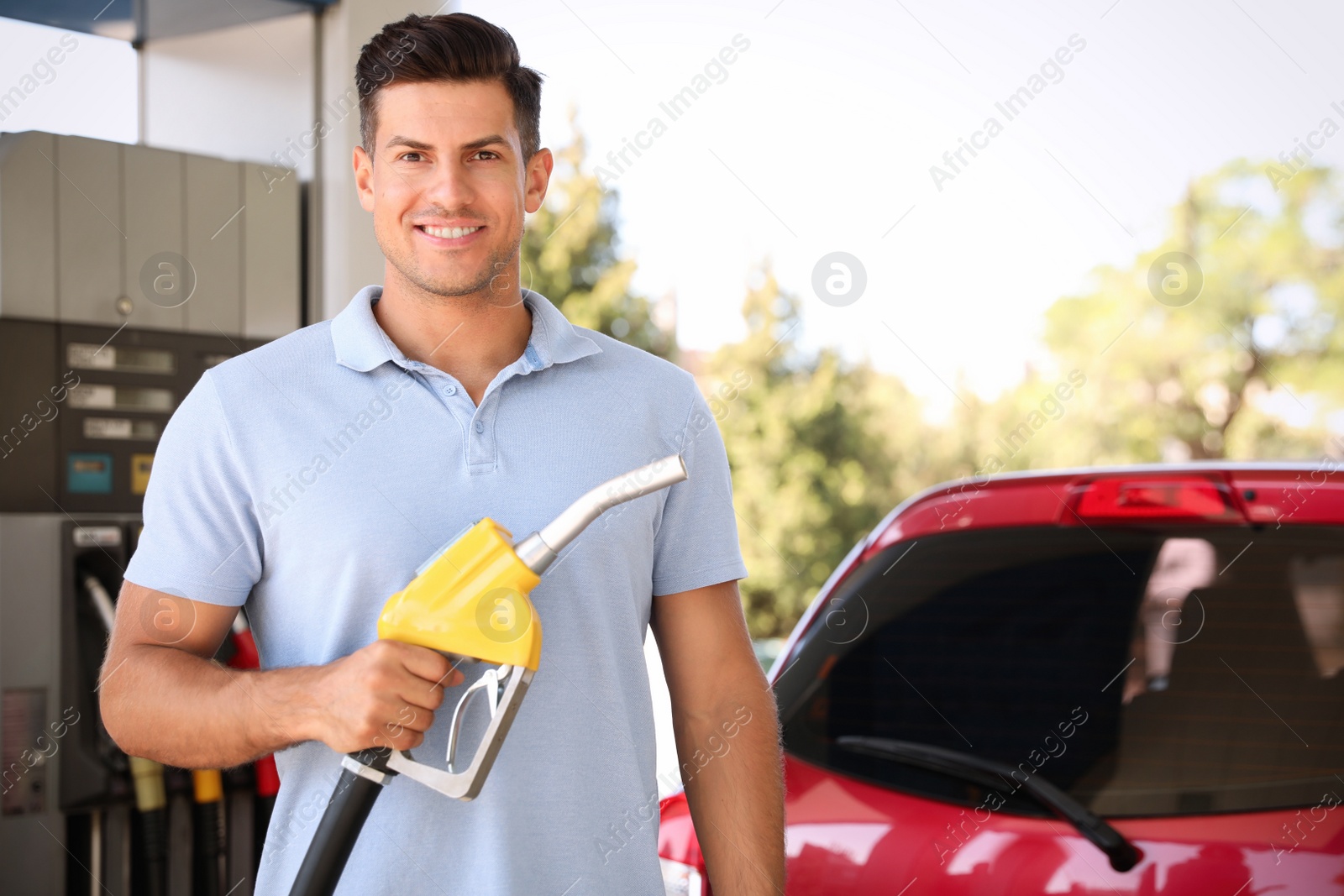 Photo of Man with fuel pump nozzle at self service gas station