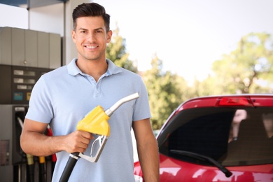 Man with fuel pump nozzle at self service gas station