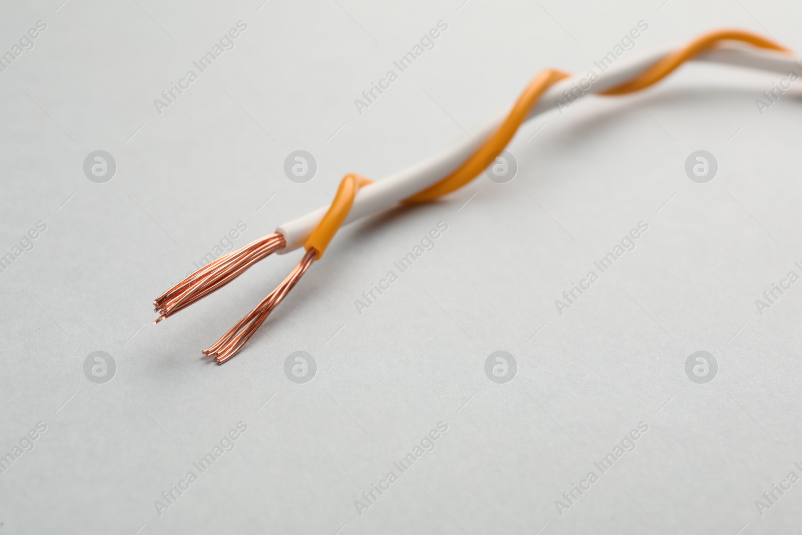 Photo of Two twisted electrical wires on light background, closeup