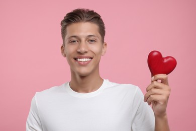 Happy man holding red heart on pink background