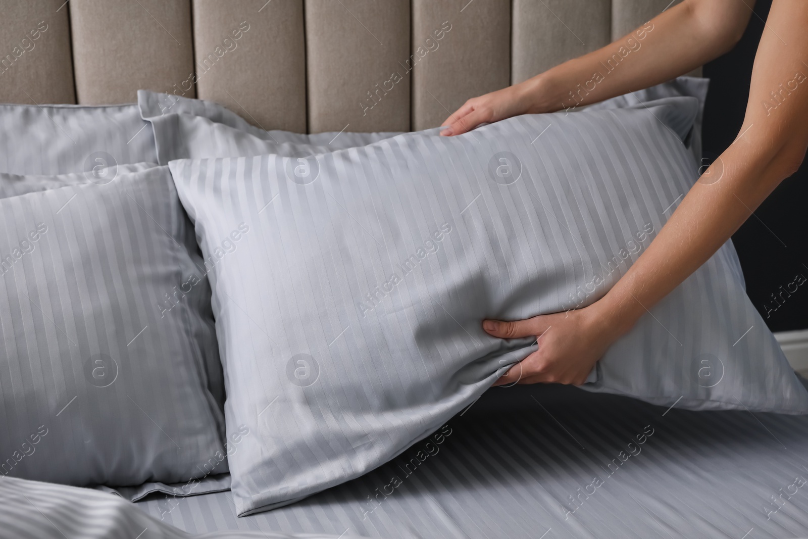 Photo of Woman putting soft pillow on bed, closeup