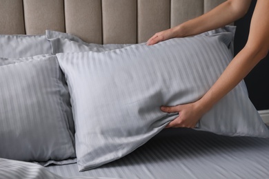 Photo of Woman putting soft pillow on bed, closeup