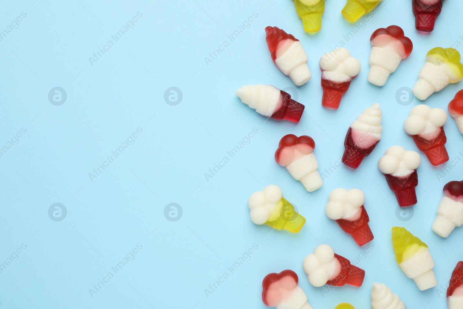 Photo of Tasty jelly candies in shape of ice cream on light blue background, flat lay. Space for text