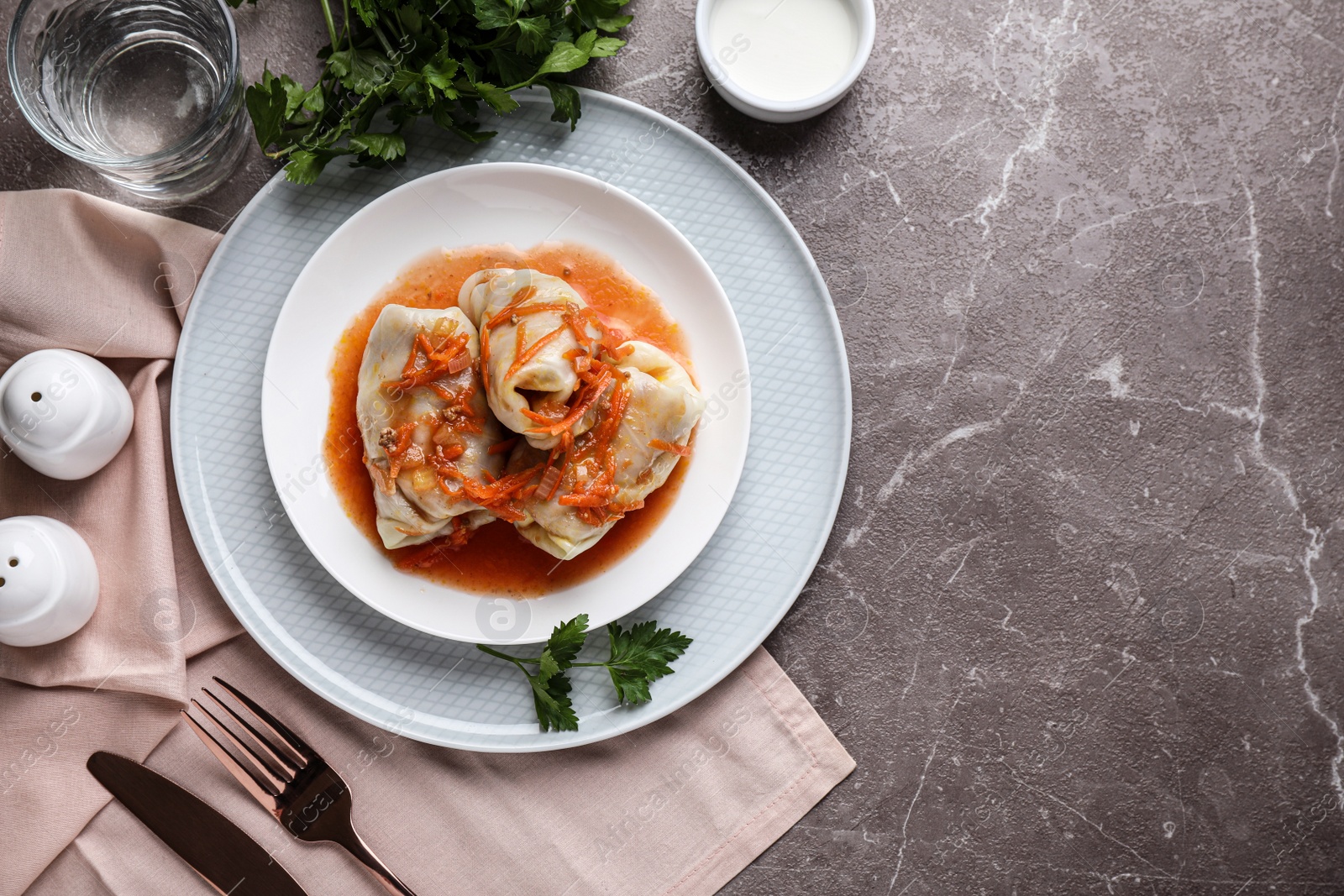 Photo of Delicious cabbage rolls served on grey marble table, flat lay