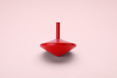 Photo of One bright spinning top on beige background. Toy whirligig
