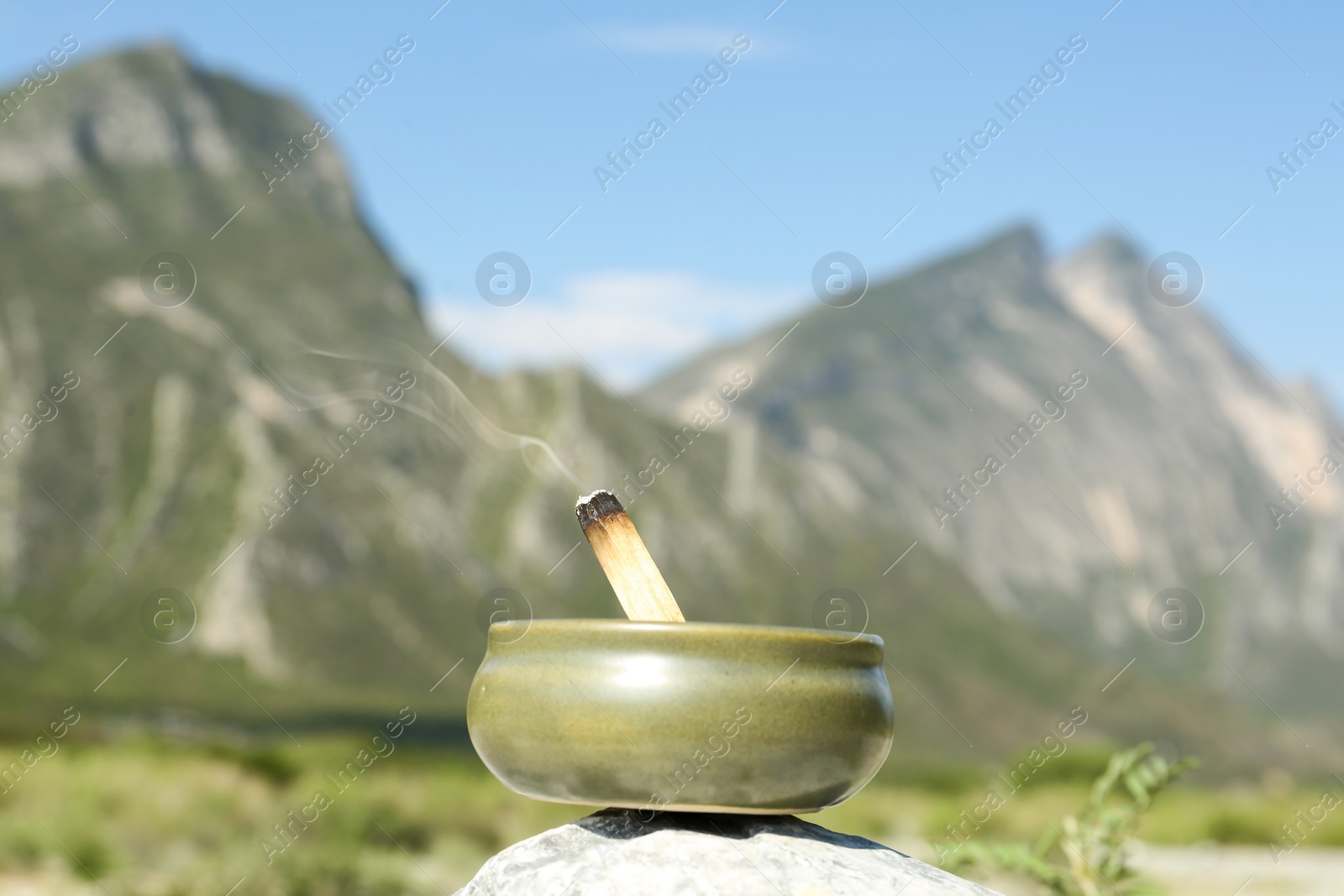 Photo of Burning palo santo stick on stone surface in high mountains