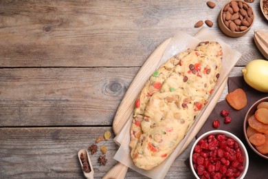 Photo of Unbaked Stollen with candied fruits and raisins on wooden table, flat lay. Space for text
