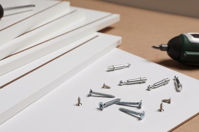 Photo of White furniture assembly parts and different metal fasteners on brown background