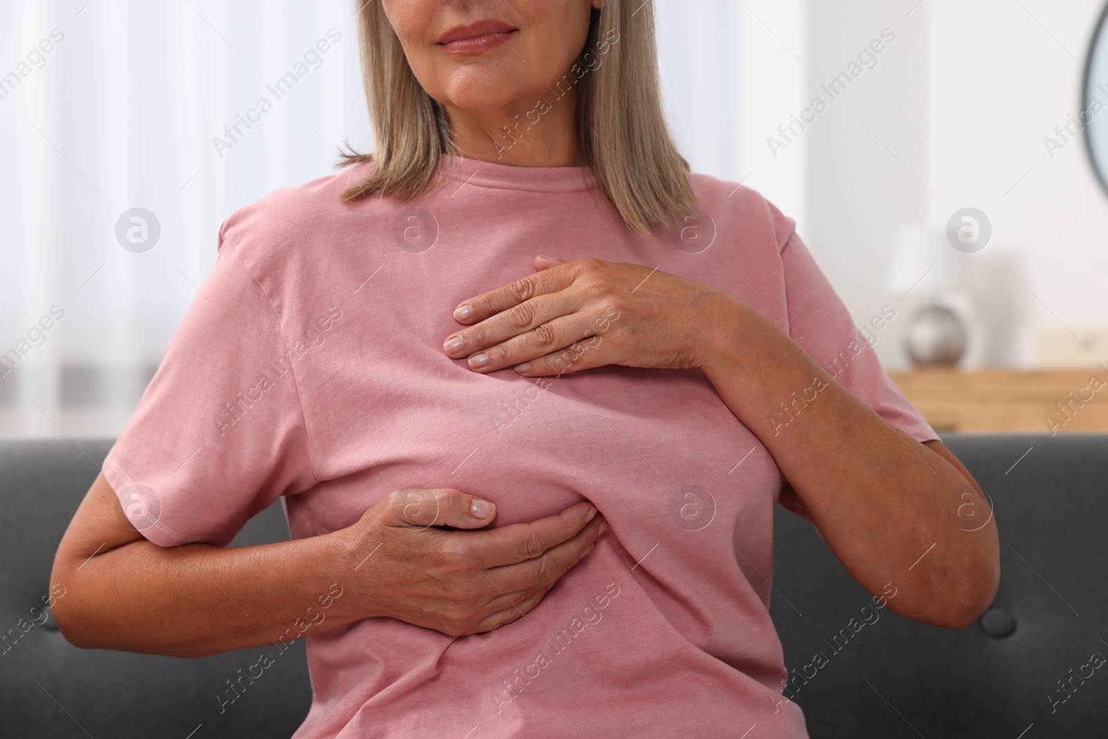 Photo of Woman doing breast self-examination at home, closeup