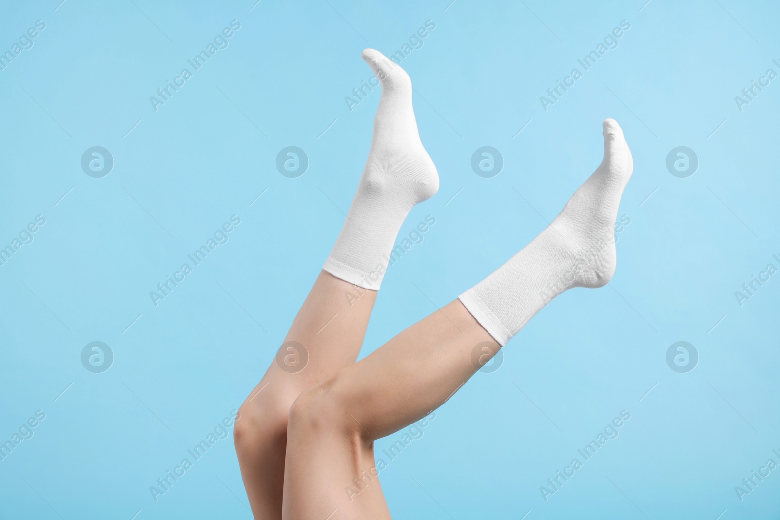 Photo of Woman in stylish white socks on light blue background, closeup