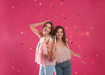 Portrait of happy friends with champagne in glasses and confetti on color background