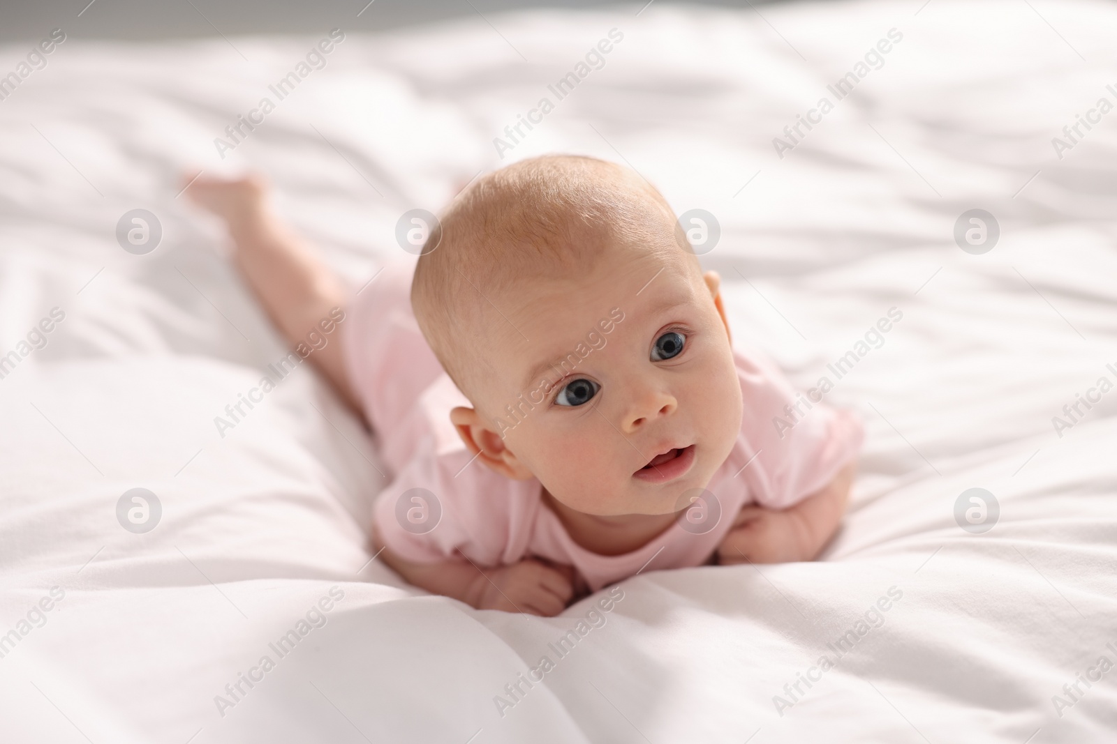 Photo of Cute little baby lying on white sheets