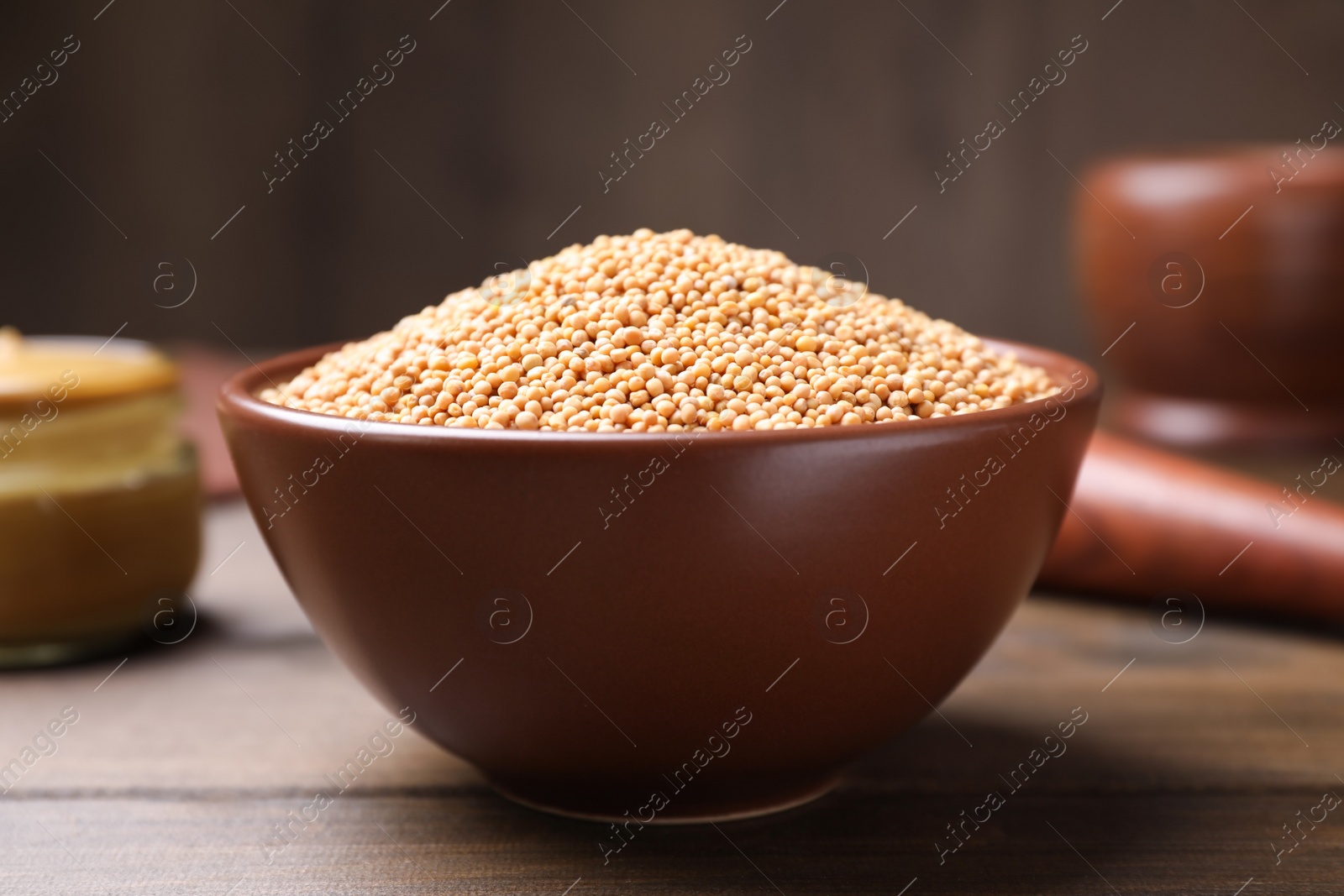 Photo of Mustard seeds in bowl on wooden table