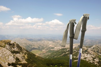 Image of Trekking poles and beautiful view of mountains on sunny day. Space for text