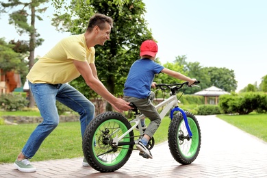 Dad teaching son to ride bicycle outdoors