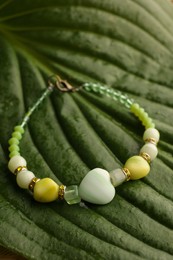 Photo of Beautiful bracelet with gemstones on green leaf