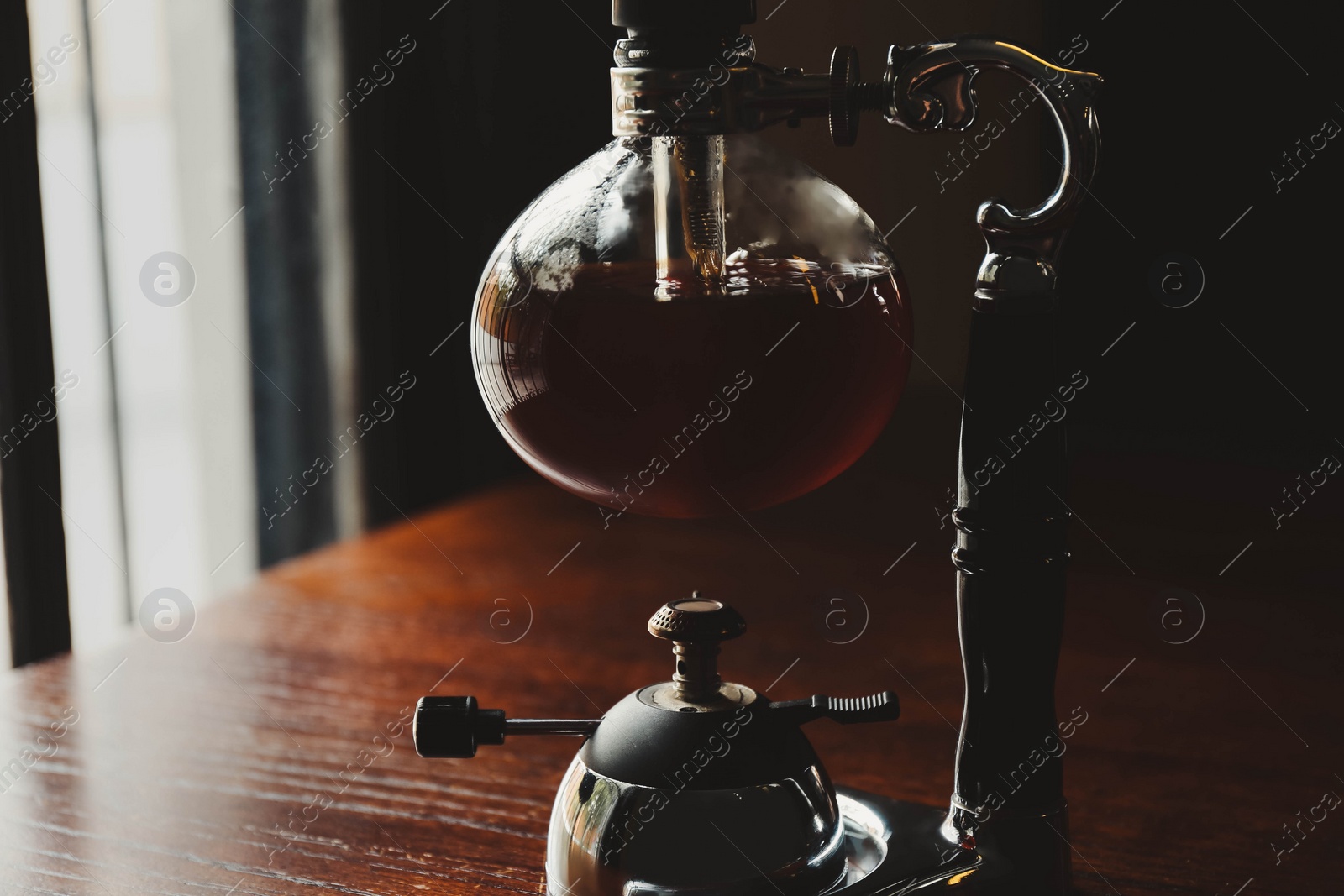 Photo of Vacuum coffee maker on wooden table in cafe