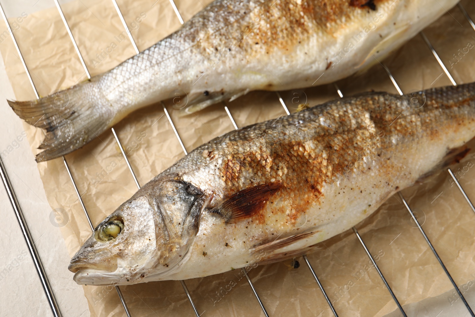 Photo of Baked fish on light marble table, closeup