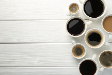 Photo of Different coffee drinks in cups on white wooden table, flat lay. Space for text