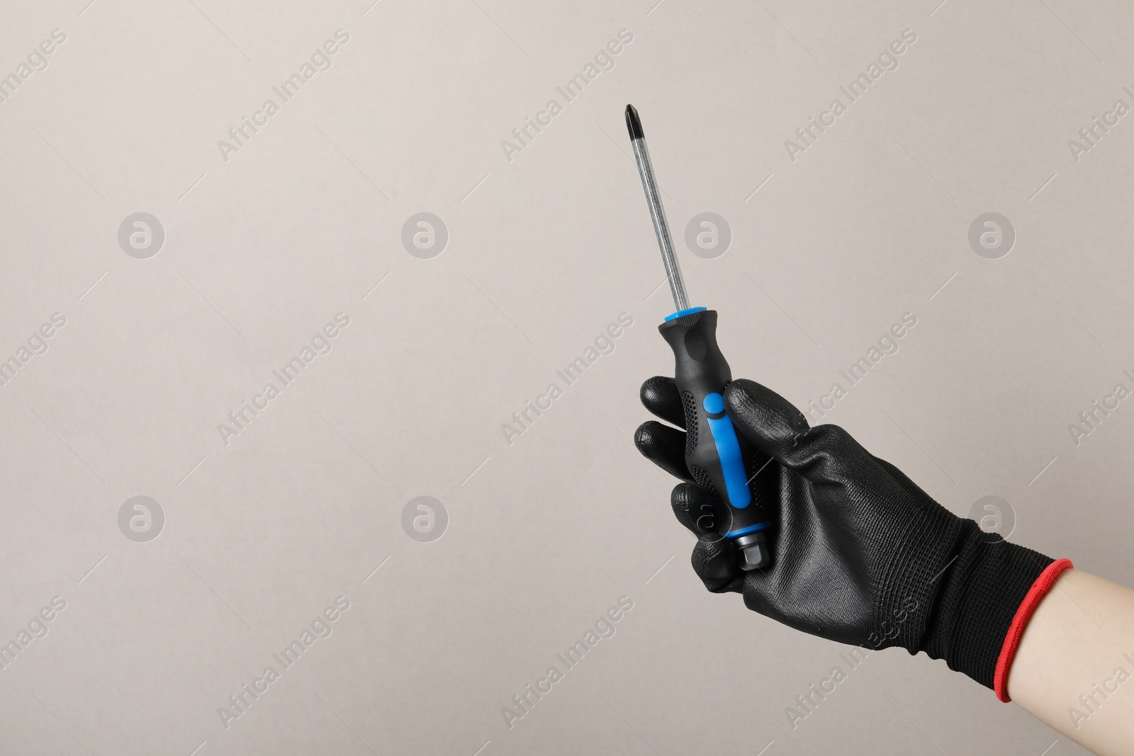 Photo of Woman holding screwdriver on grey background, closeup. Space for text