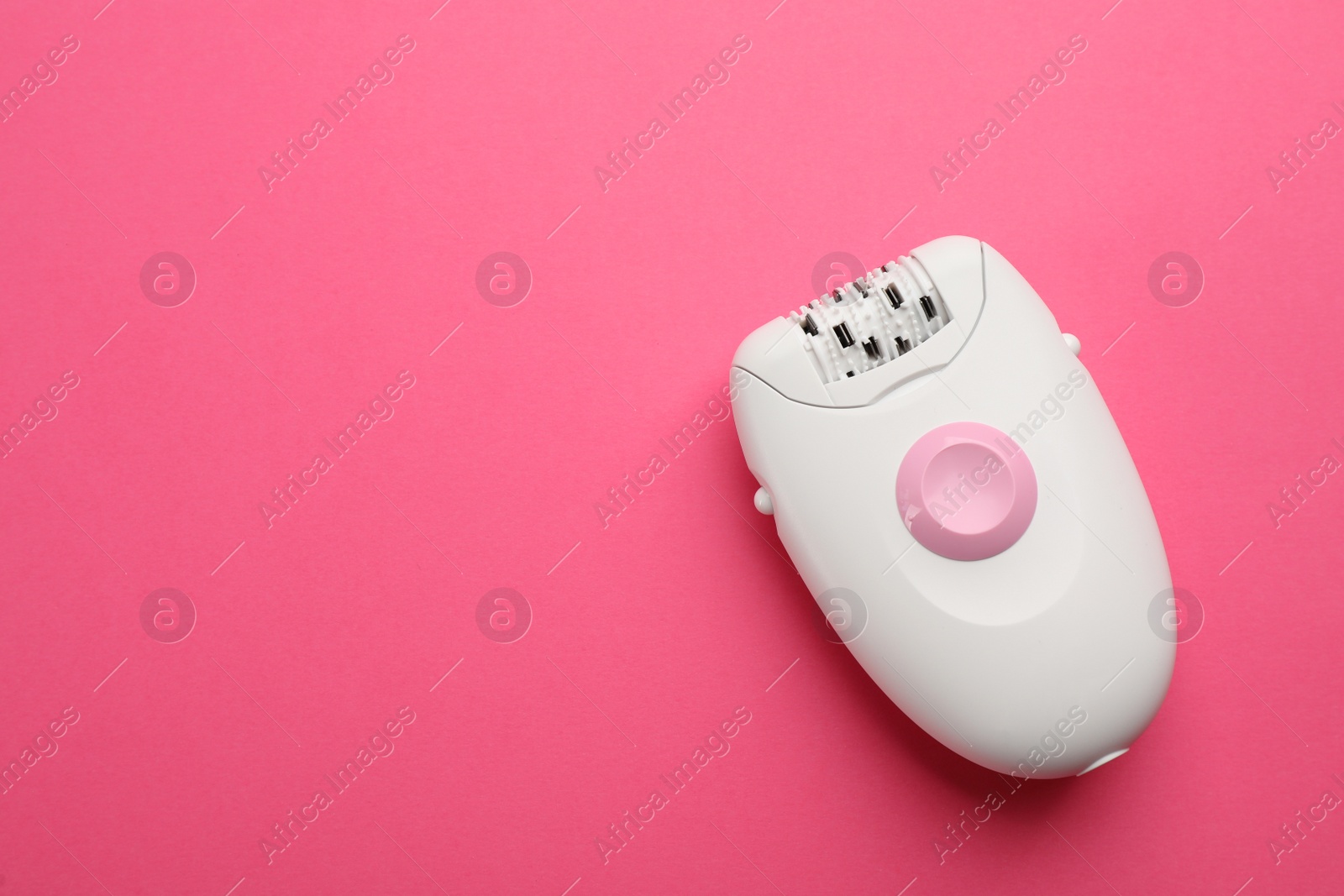 Photo of Modern epilator on pink background, top view. Space for text