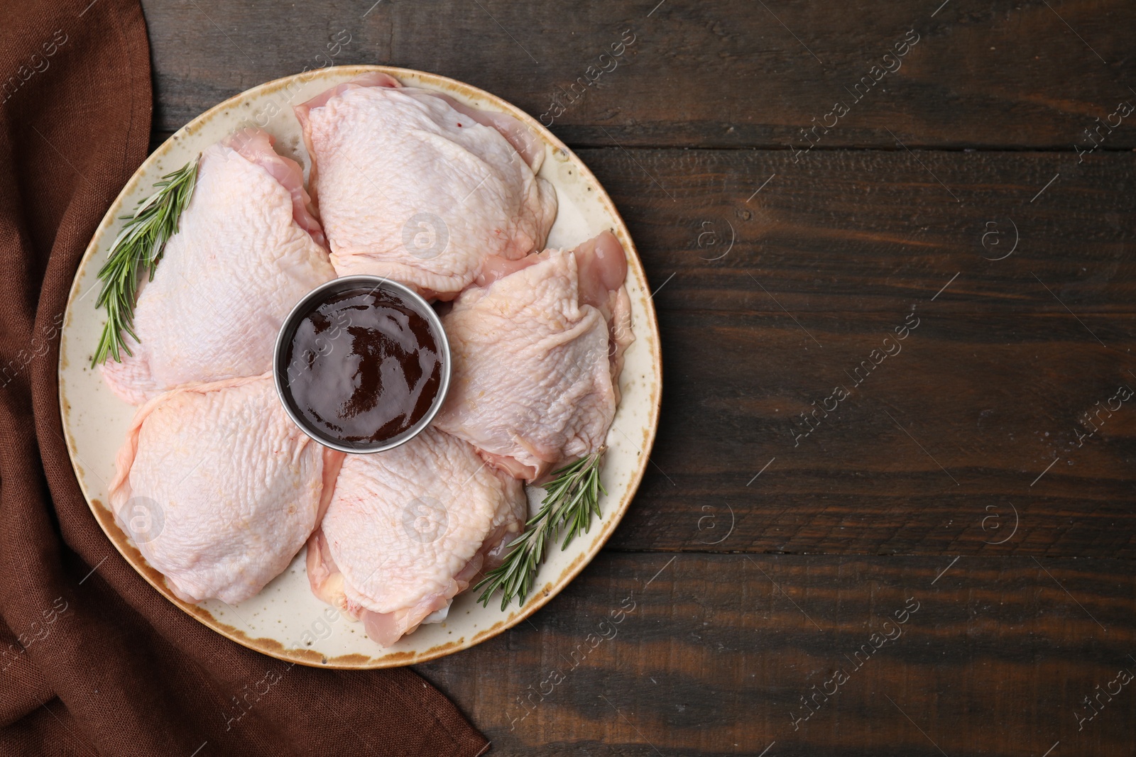 Photo of Plate with fresh marinade, raw chicken and rosemary on wooden table, top view. Space for text