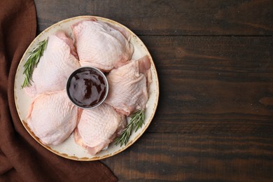 Photo of Plate with fresh marinade, raw chicken and rosemary on wooden table, top view. Space for text