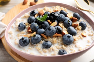 Tasty oatmeal porridge and ingredients served on table, closeup. Healthy meal